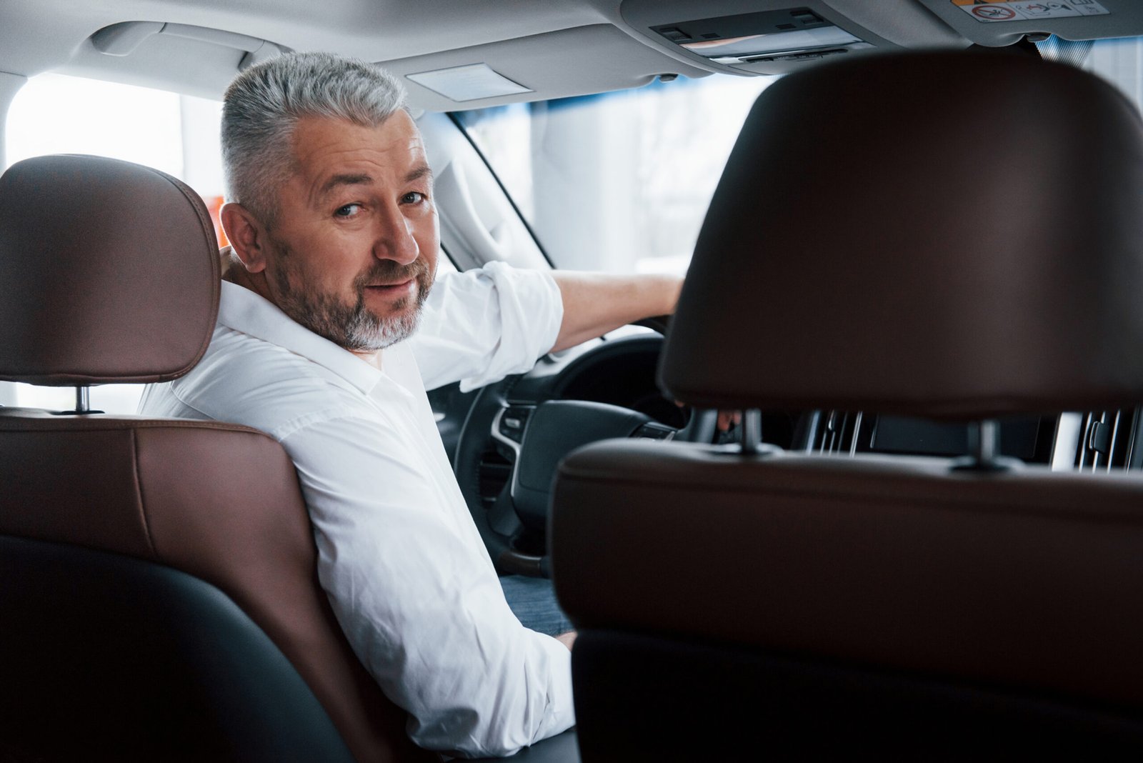 conception success joyful bearded man white shirt looks back while sitting modern car scaled